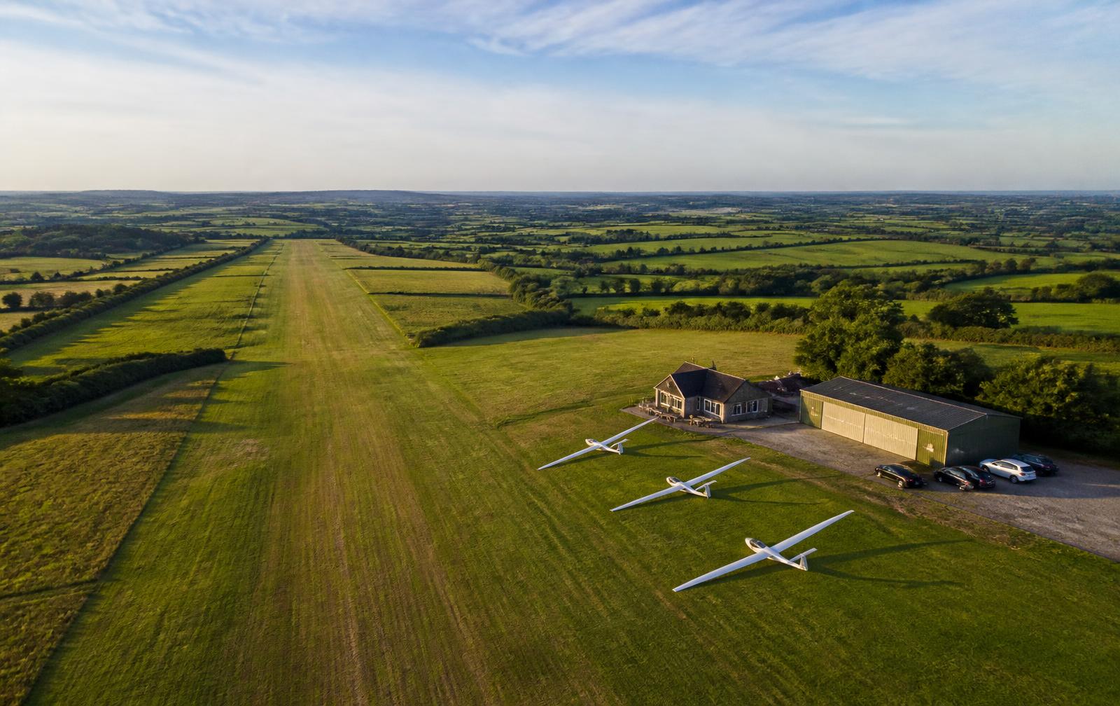 Aerial view of Vale Airfield showing the grass runway, hangars, clubhouse and gliders lined up on the field
