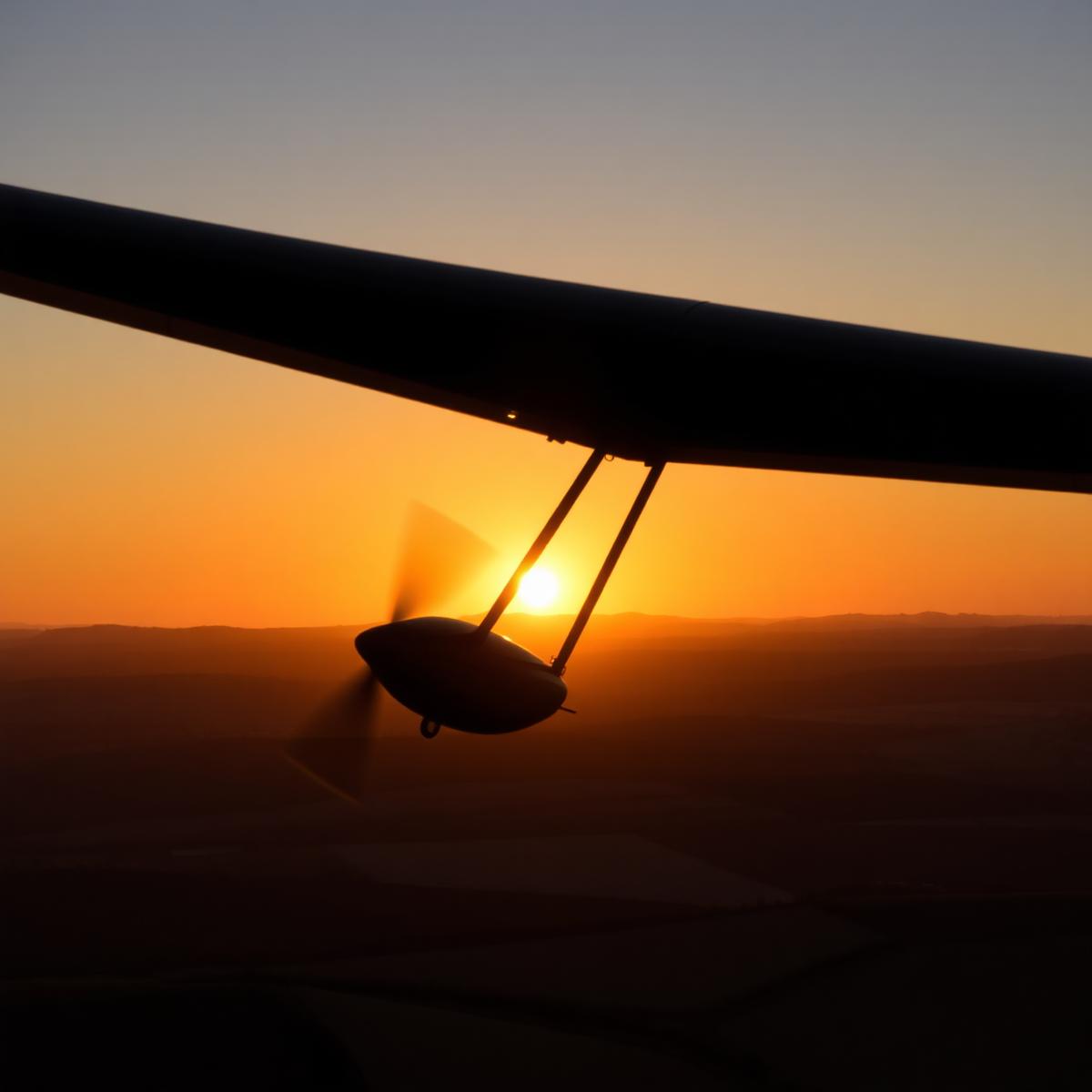 A glider wing silhouetted against a Cotswold sunset